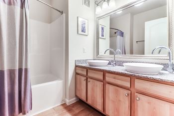 A bathroom with a white tub, wooden cabinets, and a large mirror.